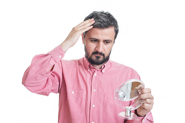 istock Man worried about gray hair looking in a mirror 542710996