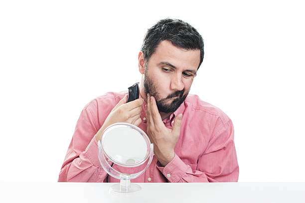 istock Young man shaving with electric razor 542711658