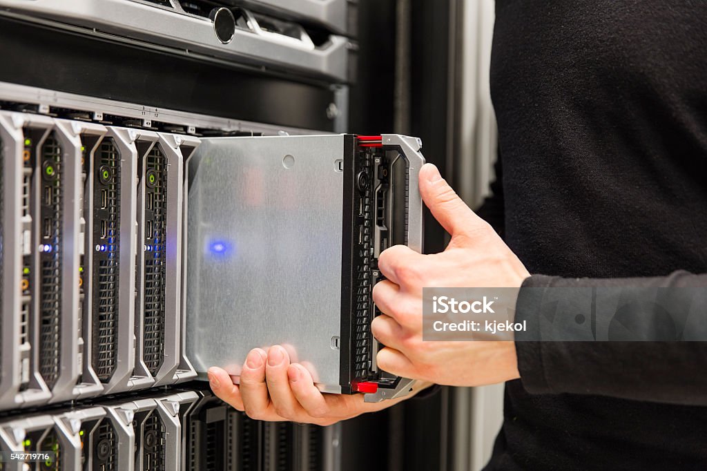 IT consultant install blade server in large datacenter It engineer or consultant working with blade server installation in data rack. Shot in enterprise datacenter. Computer Network Stock Photo