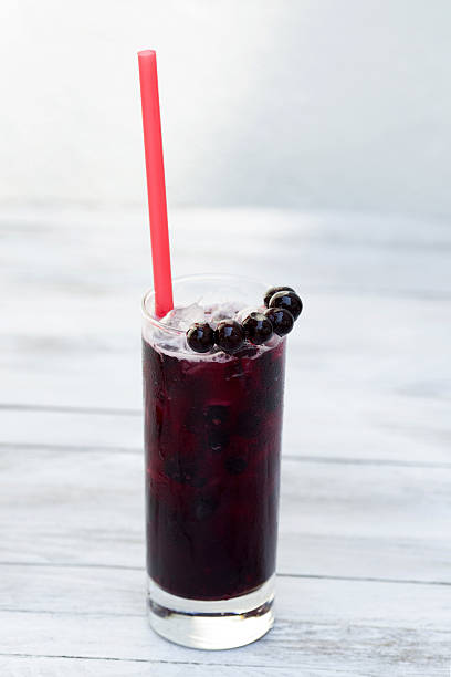 istock Blackcurrant lemonade in a glass with ice on wood background 542721254