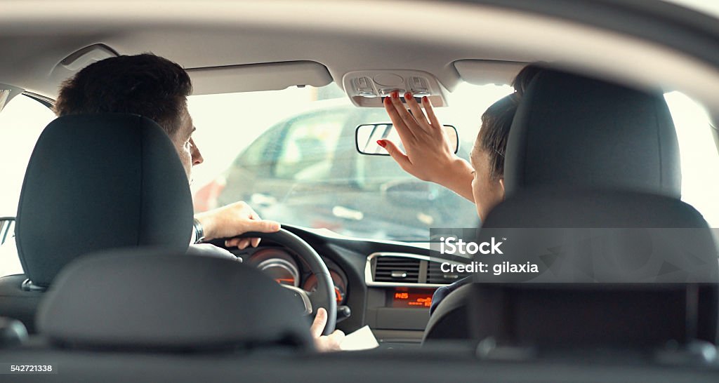 Buying a car. Closeup rear view of car saleswoman sitting in a car with a customer and showing some features of the cabin. Shot through open trunk. Discussion Stock Photo