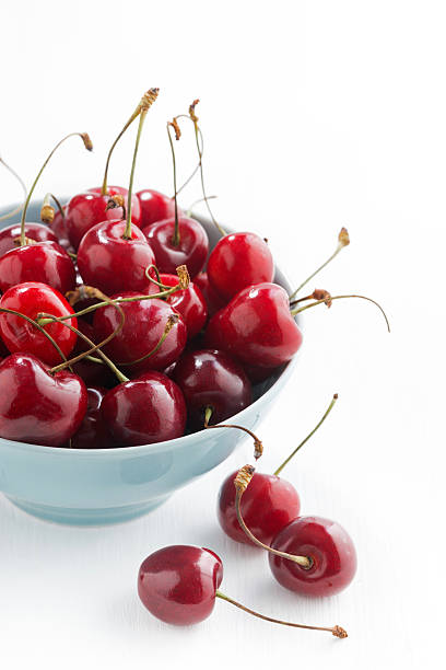 istock bowl of fresh cherries on a white background, vertical 542723882