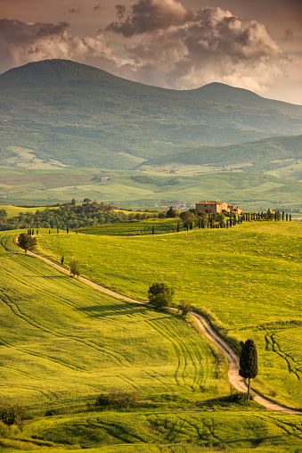 Winding road in Tuscany with farmhause at sunset