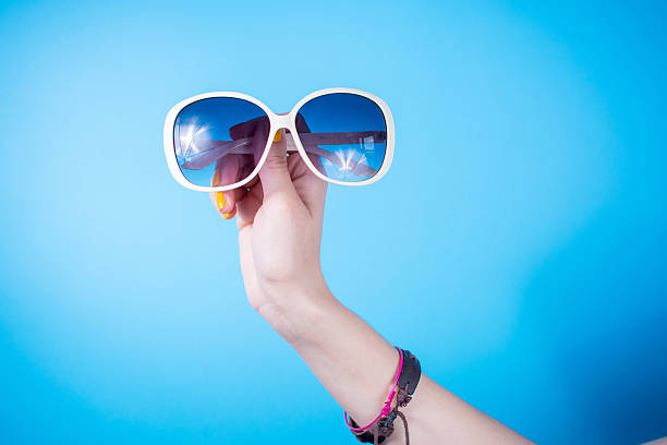istock Woman hand holding sunglasses against blue background 542725190