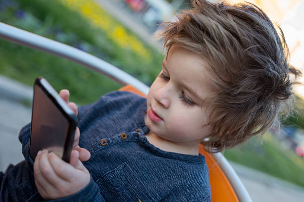 携帯電話でテキストメッセージを入力する小さな男の子。 - child text messaging little boys male ストックフォトと画像