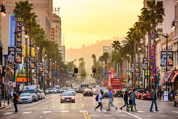 Hollywood California Streets Los Angeles, CA, USA - March 1, 2016: Pedestrians cross traffic on Hollywood Boulevard at dusk. The road serves as a theater district and major tourist attraction. hollywood california stock pictures, royalty-free photos & images