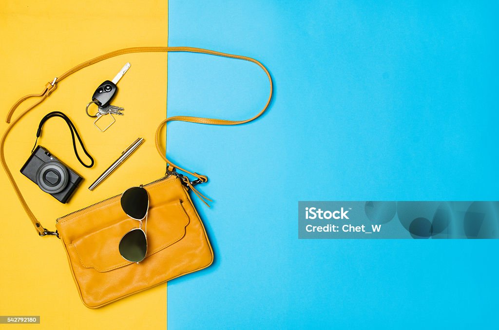 Woman's accessories lying flat on textured fabric background Woman's accessories lying flat on textured fabric background. Blue and yellow pastel colors with copy space around products. Horizontal image or photograph. Purse Stock Photo