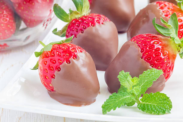 istock Strawberries covered with milk chocolate on a white plate, closeup 542795416