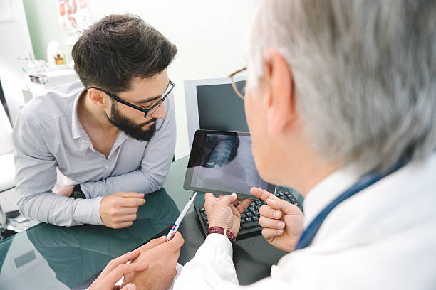 mature homme médecin à l'aide d'une tablette numérique dans ses diagnostic. - doctor digital display digital tablet healthcare and medicine photos et images de collection