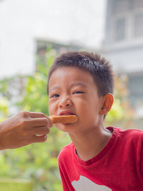 istock Asian boy eat a bread by another hand 542797734