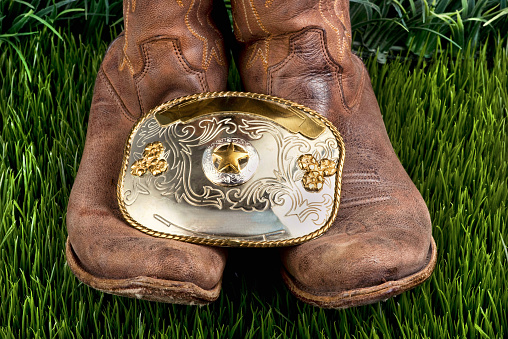 American cowboy with his boots and big silver cowboy belt buckle.