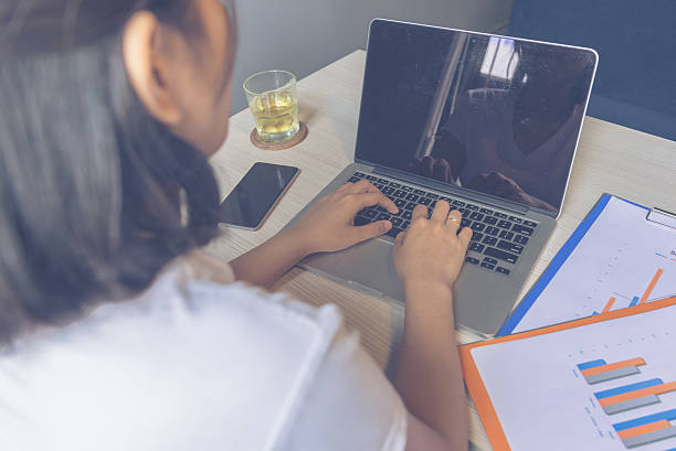 istock Asian businesswoman using laptop with smartphone and reports beside 542801484