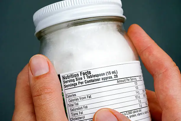 Photo of Reading nutrition facts on organic coconut oil jar