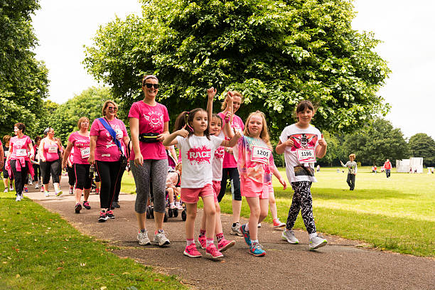 Race for Life - Charity fun run Liverpool, UK - June 26, 2016: Race for Life is a series of fundraising events for women only, organised by British charity Cancer Research UK. They involve running, jogging or walking a 5-kilometre course and raising sponsorship for doing so. The money raised funds cancer research in all 200 types of cancer. Groups and Family undertake their run or walk. walking for a cause stock pictures, royalty-free photos & images