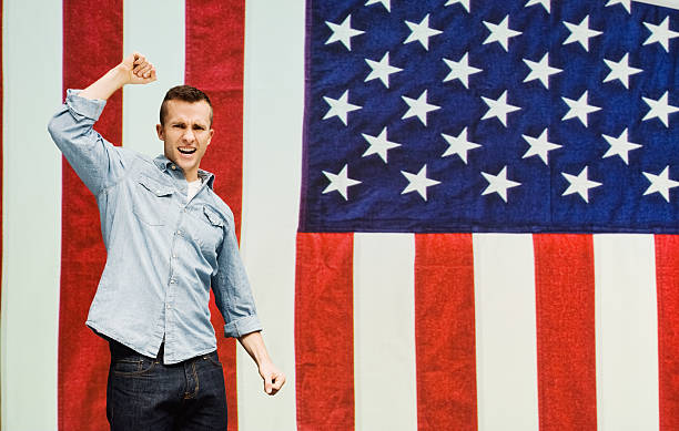 istock Man cheering in front of flag 542812502