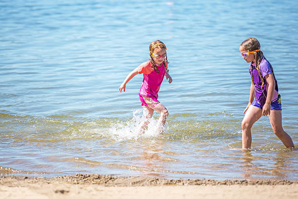 istock Two Young Girls Playing in Water at Beach 542815266