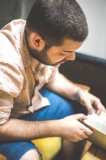 istock man is sitting on a sofa and reading a book 542815348