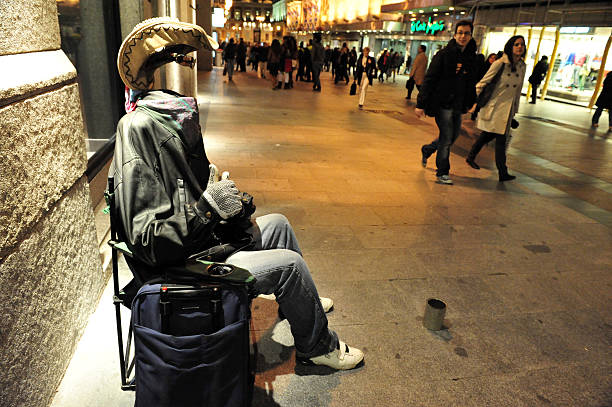 Milan, Italy - December 11, 2016: Living statue of a man painted in gold color and seated on a invisible chair. On the street.