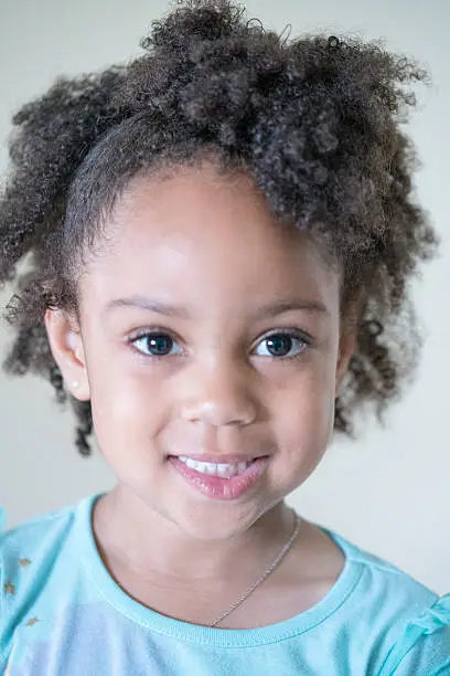 African American young girl/child with natural hair close-up headshot as a full headshot with a semi-smile.
