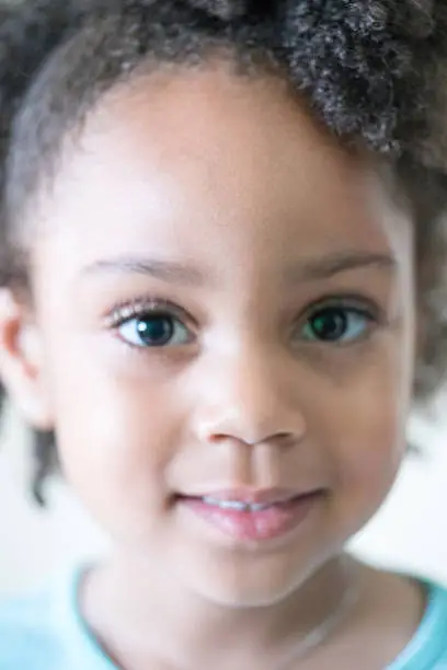 African American young girl/child with natural hair pose close-up headshot with contrast lighting.