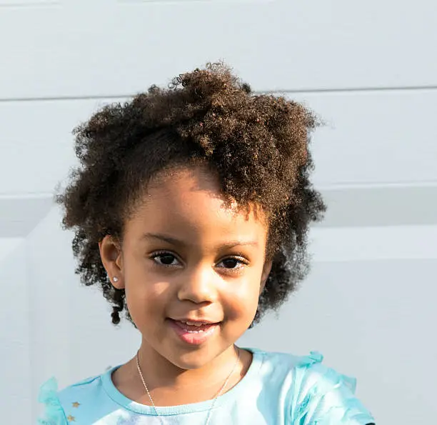 African American young girl/child with natural hair outside smiling with natural sunlight with contrast lighting.
