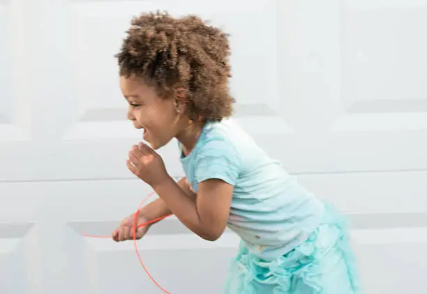 African American young girl/child with natural hair running with rope-item excited to play.