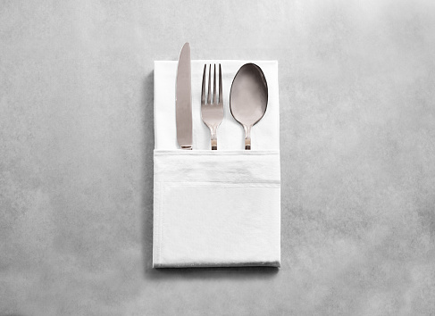 Blank white restaurant cloth napkin mockup with silver cutlery set, isolated. Knife fork and spoon in clear textile towel mock up template. Cafe branding identity clean napkin surface for logo design.