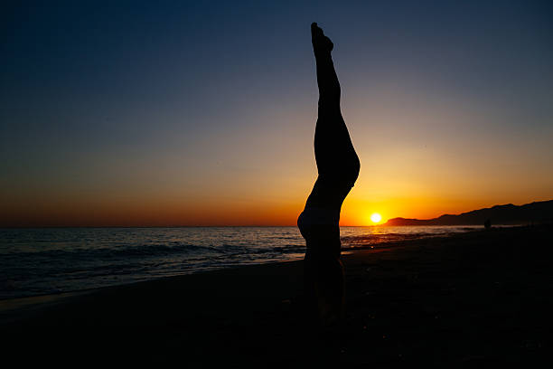 istock Young woman standing on her hands at the beach. 542826516
