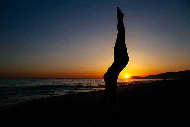 istock Young woman standing on her hands at the beach. 542826544