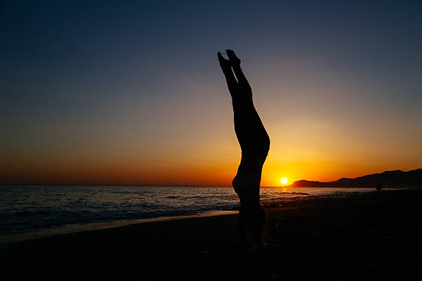 istock Young woman standing on her hands at the beach. 542826606