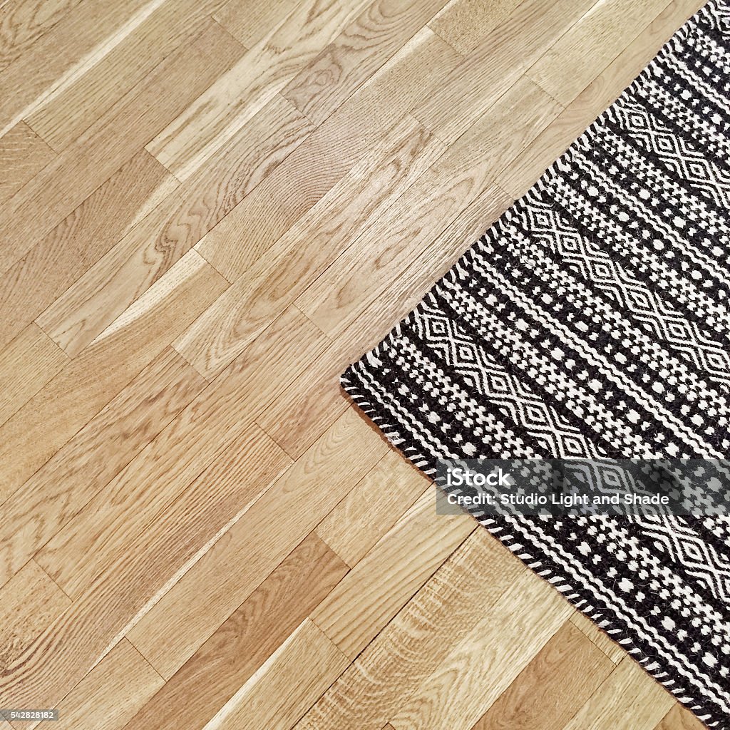 Stylish black and white rug on wooden floor Stylish black and white rug with ethnic design on hardwood floor. Rug Stock Photo