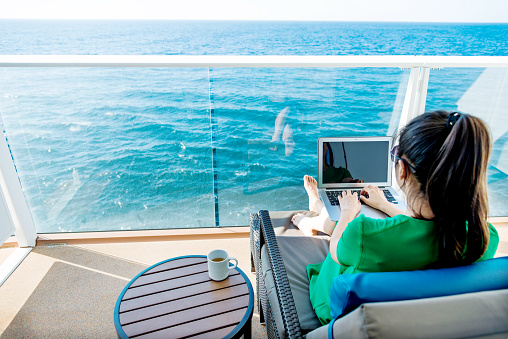 Woman working with a laptop on cruise ship.