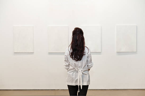 istock One woman looking at white frames in an art gallery 542831436