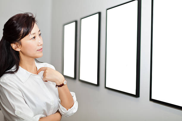 istock One woman looking at white frames in an art gallery 542831498