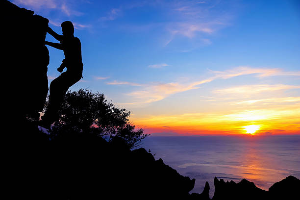 istock Photographer climbing rocks at sunset. 542832476
