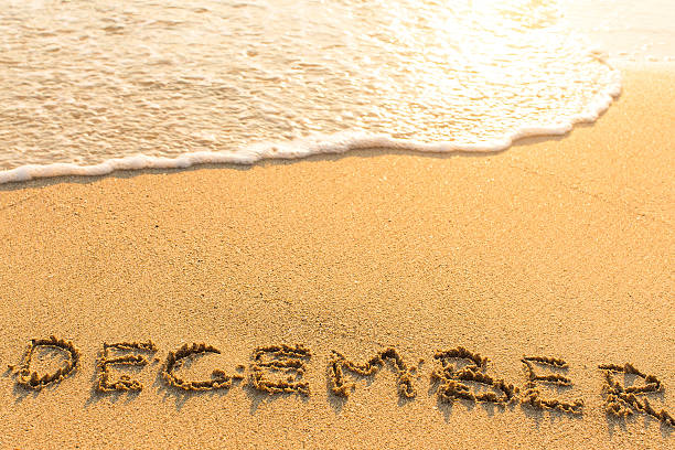 istock December - inscription on sand beach with the soft wave. 542836168