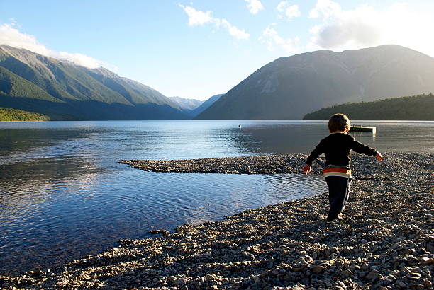 Child plays in Lake at Sunset A Pre-school Child plays at Lake Rotoiti in evening's sun. nelson city new zealand stock pictures, royalty-free photos & images