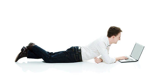 istock Smiling casual man lying and typing on laptop 542928252