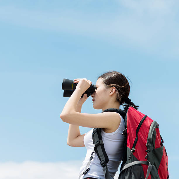 istock Female hiker looking through binoculars on top 542931476