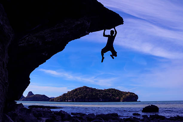 istock Man climbing rock on the beach. 542932450