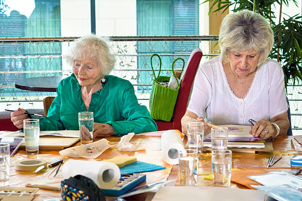 istock Two adorable senior women painting at table. 542933496