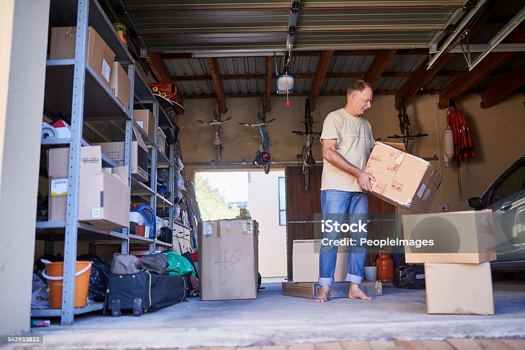 Clearing out some things Shot of a man carrying a box in a garage Garage Stock Photo