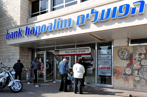 Ashkelon, Israel - January 26, 2011: People enter into Bank Hapoalim branch. It's Israelâs largest bank. The bank has about 14,000 employees worldwide. It is controlled by Arison Holdings, which is owned by Shari Arison