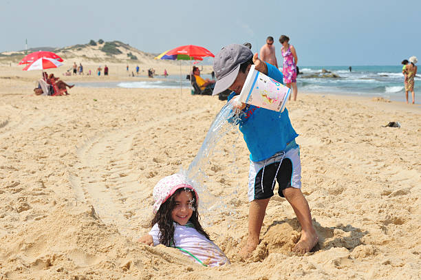 Ashdod, Israel - July 9, 2011: Little boy pours water from a bucket on his sister. The highest recorded temperatures in Israel was 129 Fahrenheit Degrees (54 Celsius) in Tirat Tsvi on June 21 1942.
