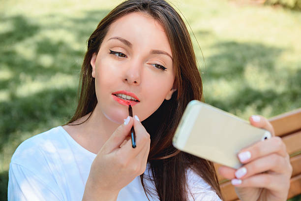 istock Woman rouge lips and looking at telephone as mirror 542949254
