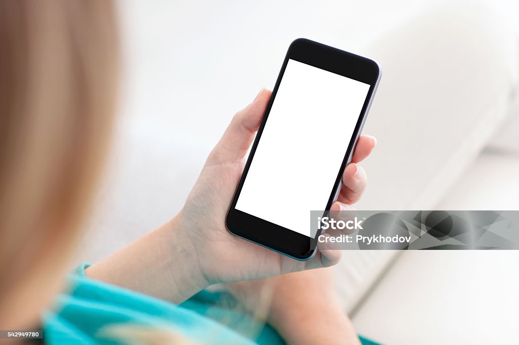 woman holding a phone with isolated screen on a sofa woman sitting on a sofa and holding a phone with isolated screen Adult Stock Photo