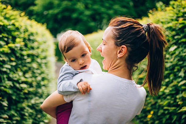 Mom holding child in park Mother holding her child in a  beautiful avenue in a park quickset stock pictures, royalty-free photos & images