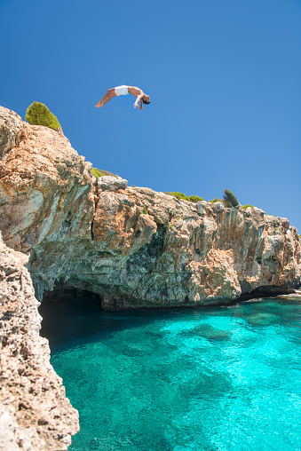 Guy jumping a backflip off a Cliff into the Ocean, Mallorca, Spain. Nikon D810. Converted from RAW.