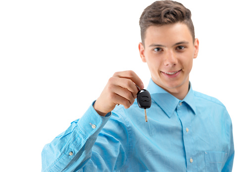 Attractive teenage boy holding car keys isolated on white background