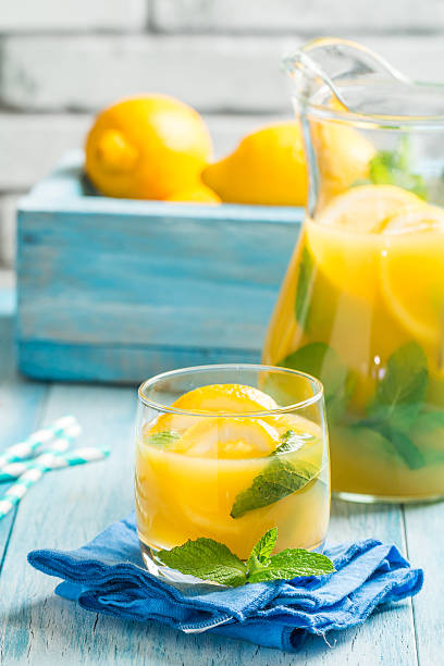 Lemonade in the jug and glass Lemonade drink. Lemonade in the jug and glass with lemons and mint on the table blue jug stock pictures, royalty-free photos & images
